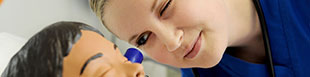woman looking into the ear of a child manikin