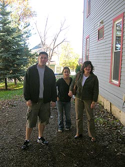 Three people standing beside a house