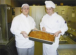 Two students holding up a pan