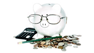 Piggy bank with glasses on surrounded by change, a pencil and a calculator